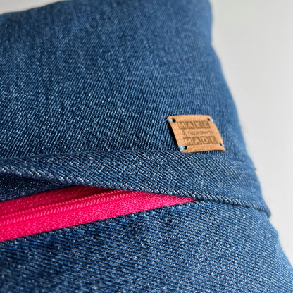 A complementary hot pink zipper is hidden beneath a denim flap on the back of the pillow, making this pillow cover easy to remove for spot cleaning.