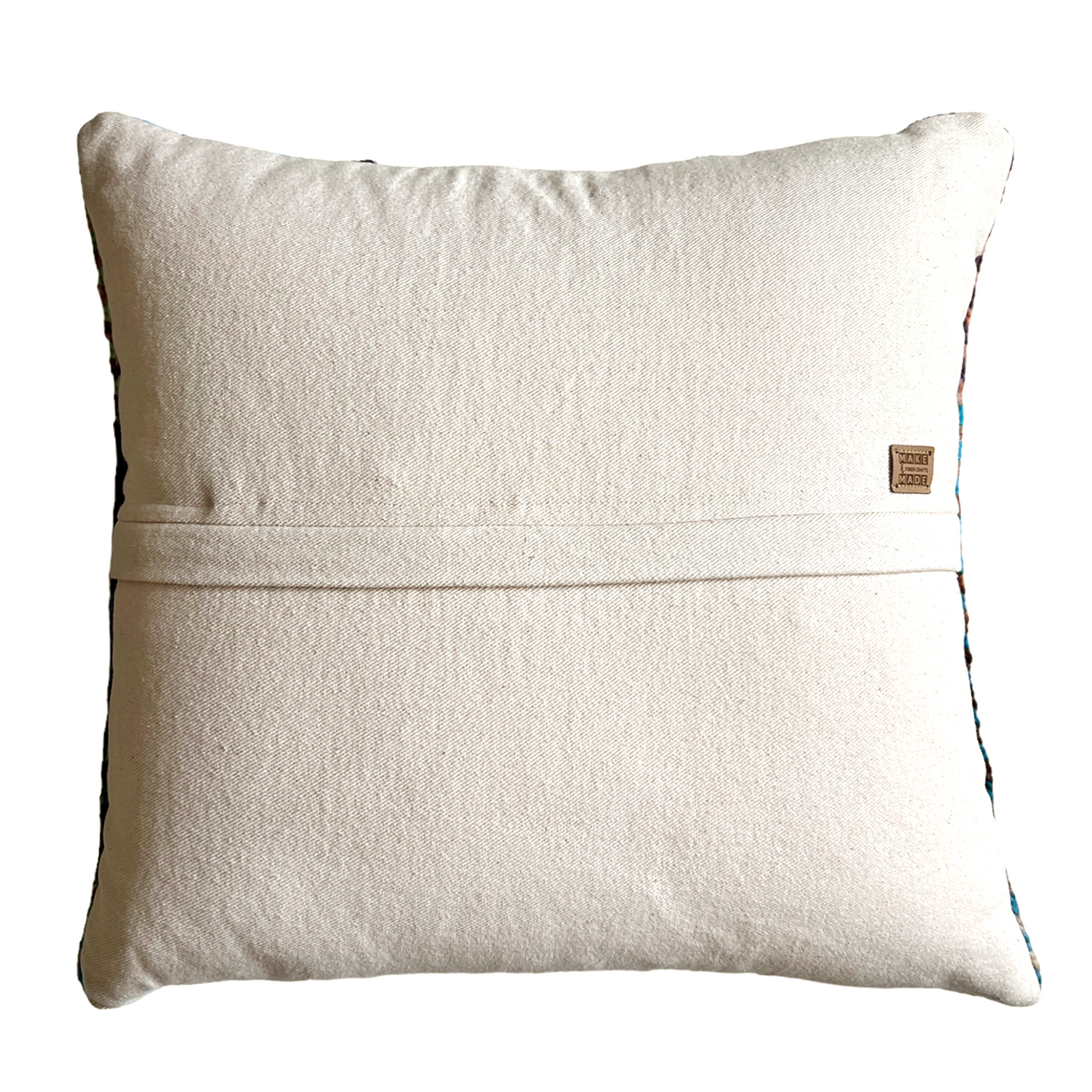 The back side of this pillow is natural bull denim. A hidden zipper runs horizontally through the middle of the pillow and includes a leather Make & Made Fiber Crafts label.