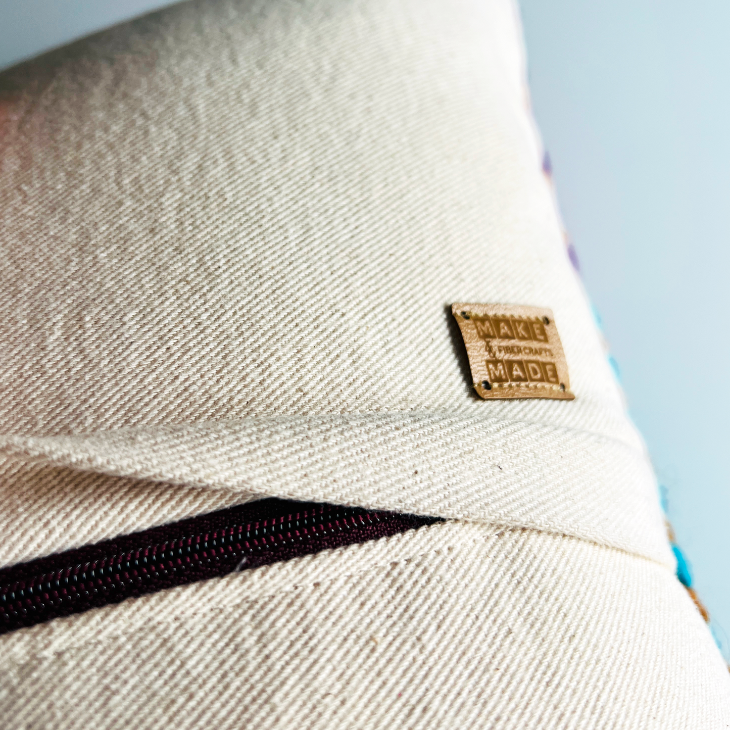 A complementary dark wine zipper is hidden beneath a denim flap on the back of the pillow, making this pillow cover easy to remove for spot cleaning.