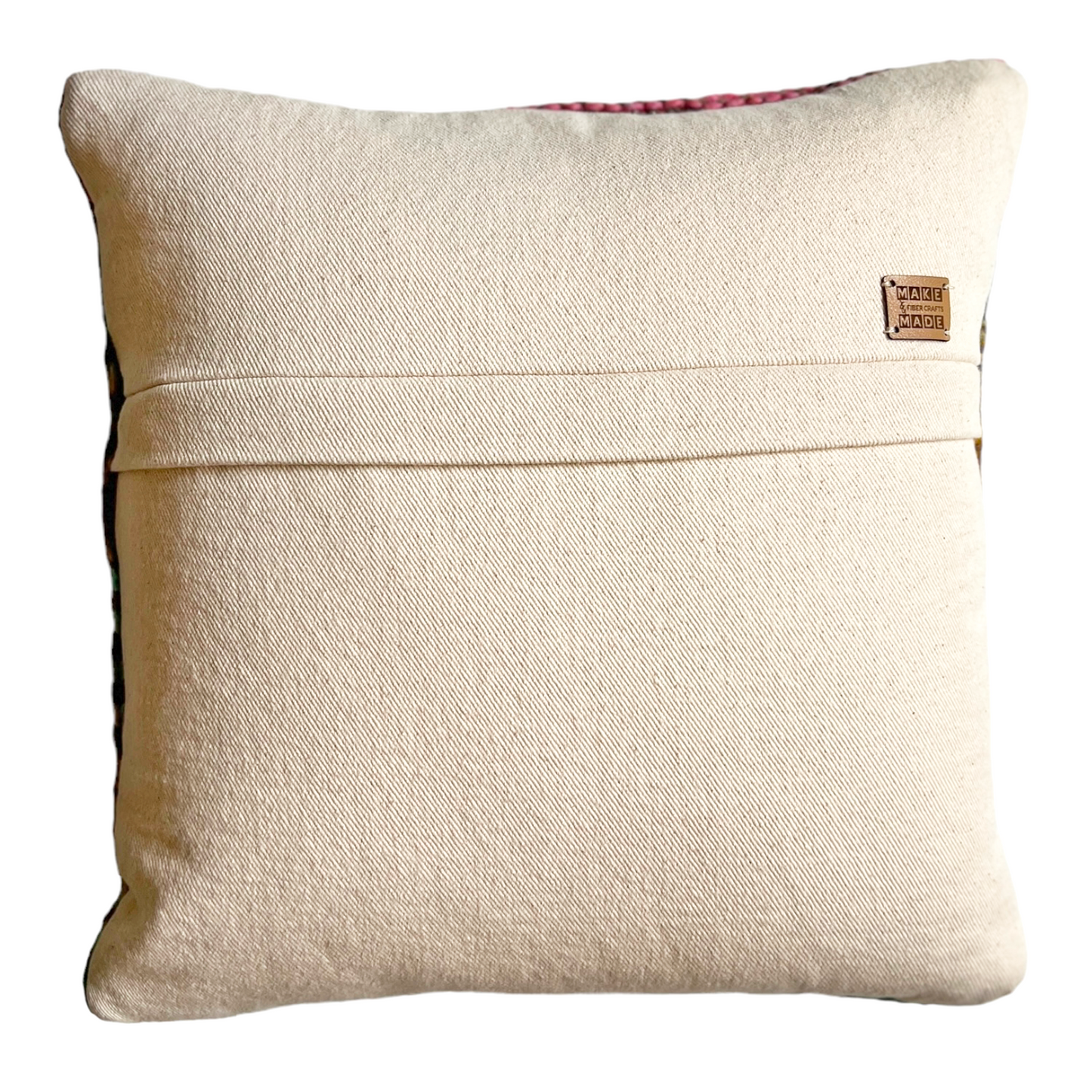 The back side of this pillow is natural bull denim. A hidden zipper runs horizontally through the middle of the pillow and includes a leather Make & Made Fiber Crafts label.