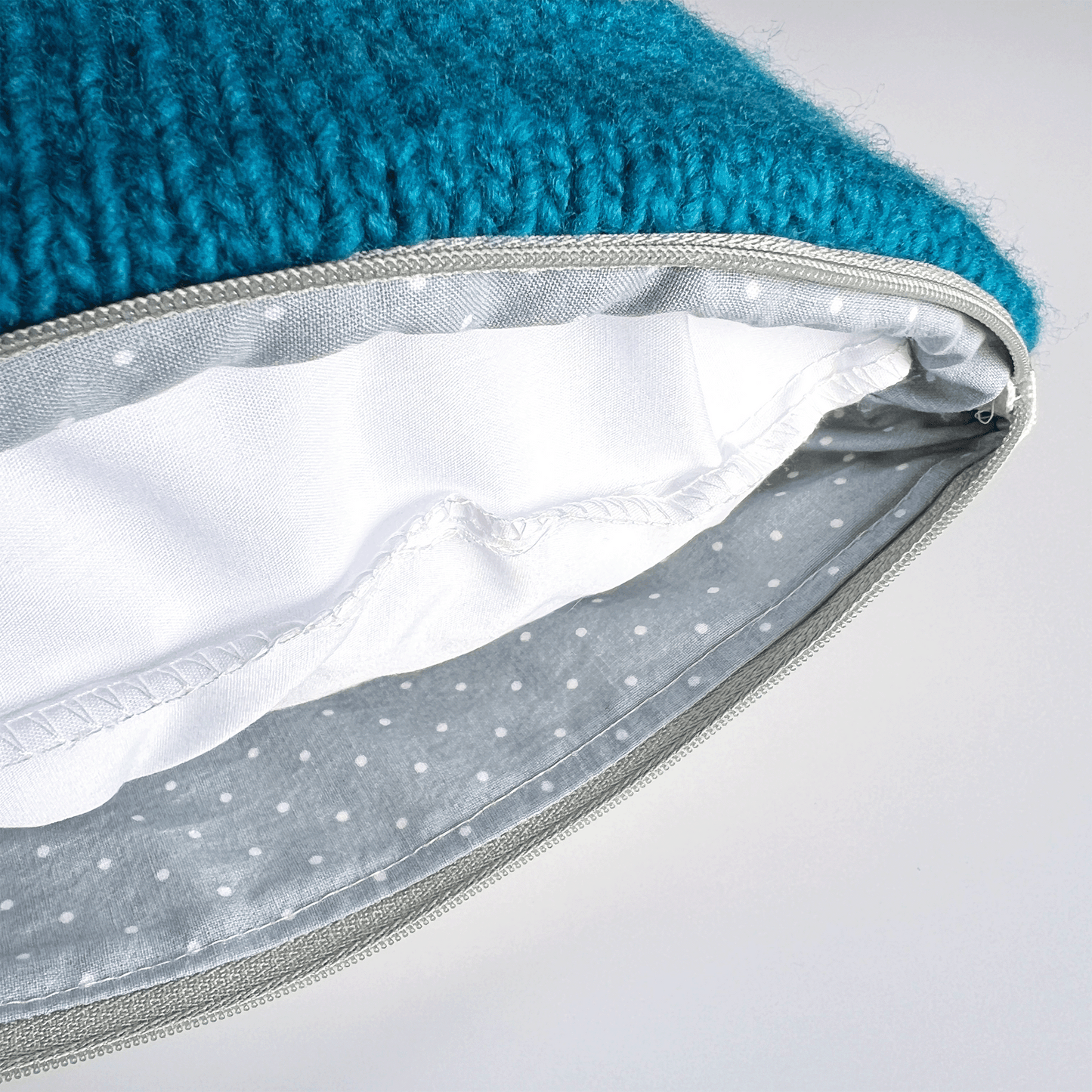 A gray and white polka dot cotton lining hides the seams in this decorative pillow with a plush, hypoallergenic synthetic down insert.