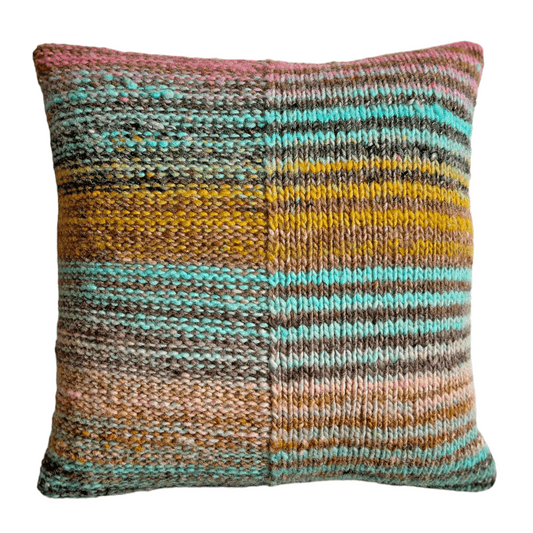 This decorative throw pillow is hand-knit with 100% wool yarn in stripes of taupe, turquoise, pink, and gold.