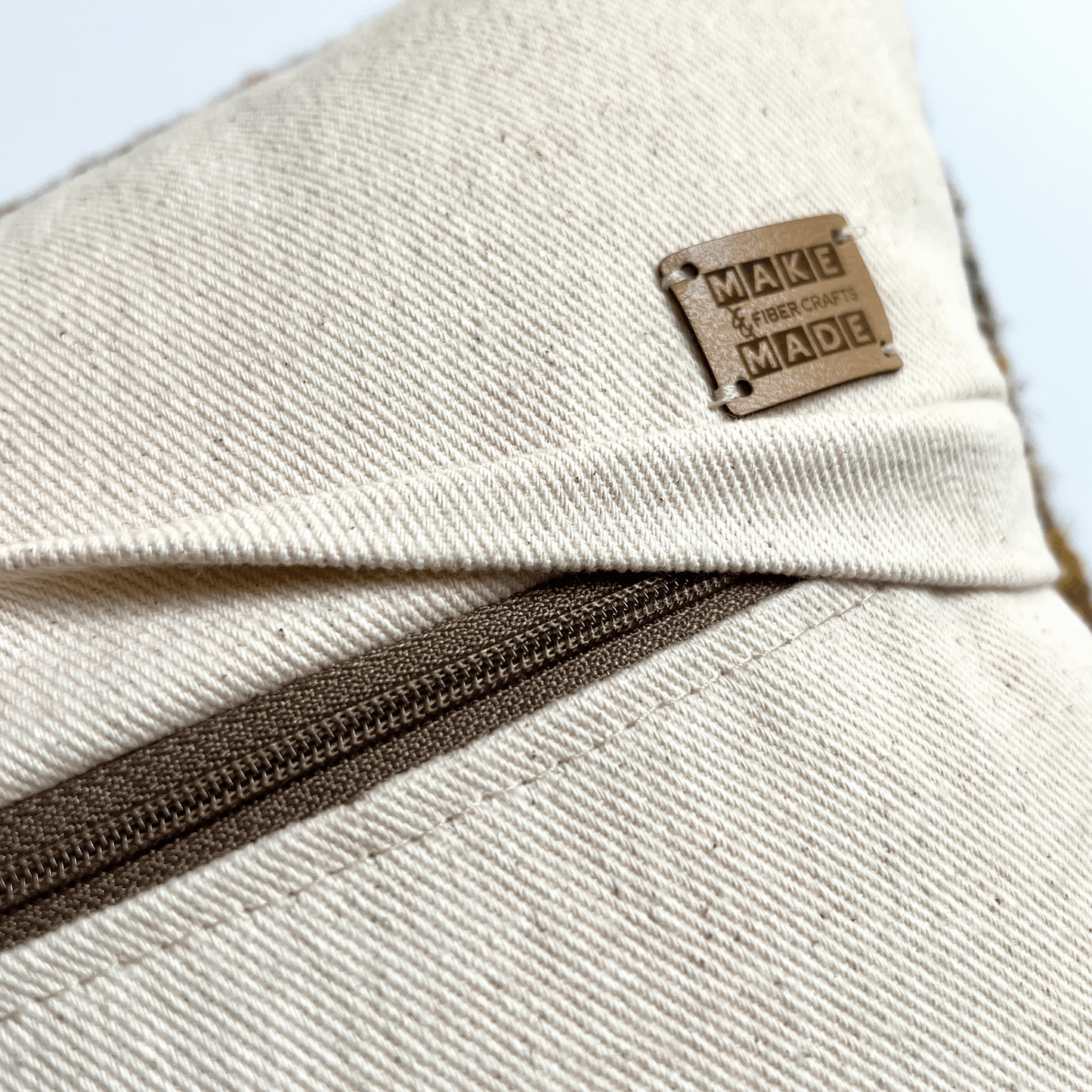 A dark taupe zipper hides beneath a 1 inch flap, rendering this hand-sewn pillow cover easy to remove for spot cleaning.
