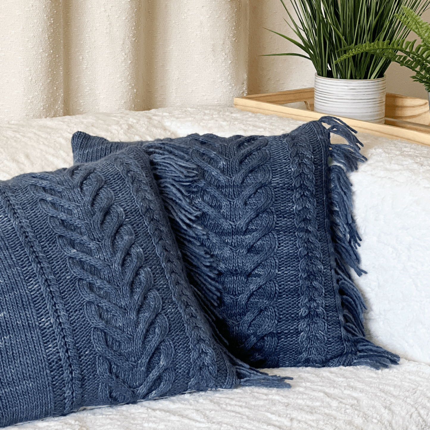 These 100% merino wool, hand-knit decorative throw pillows feature bold staghorn cables and decorative fringe hiding a side zipper.