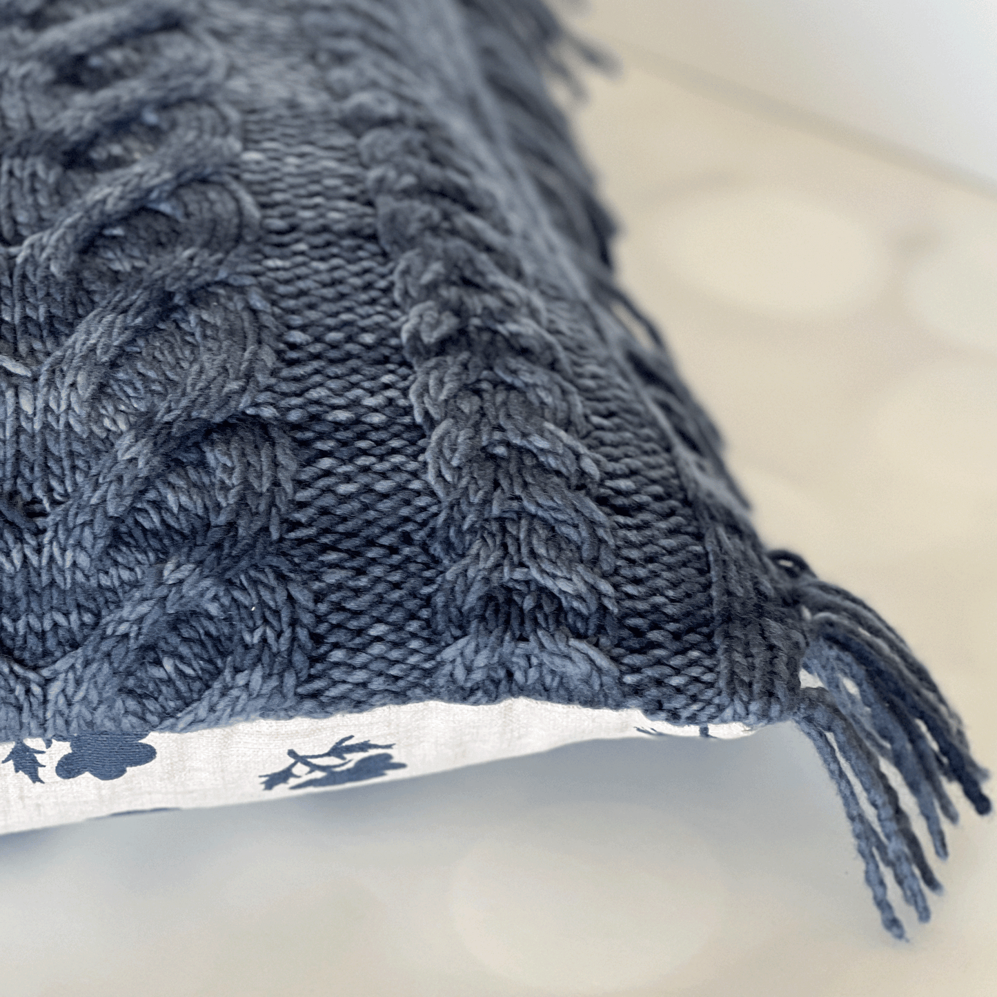 A natural cotton canvas back (with a medium-size navy floral print) complements the denim blue tonal yarn on the front of this throw pillow.