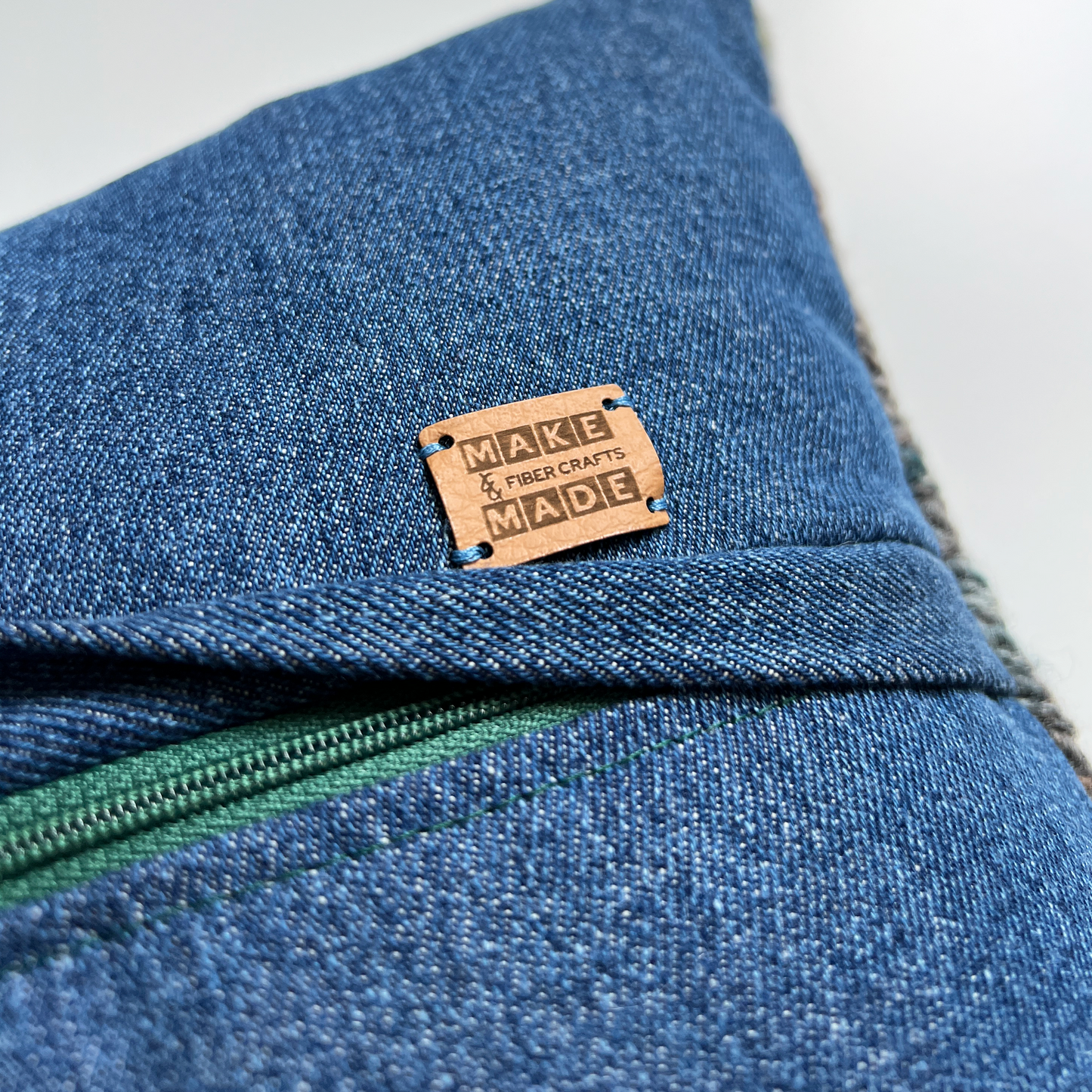 A complementary hunter green zipper is hidden beneath a denim flap on the back of the pillow, making this pillow cover easy to remove for spot cleaning.