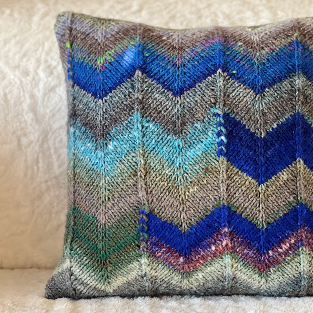This close-up of the front of this hand-knit, chevron pillow showcases the knitter's uniform stitches.