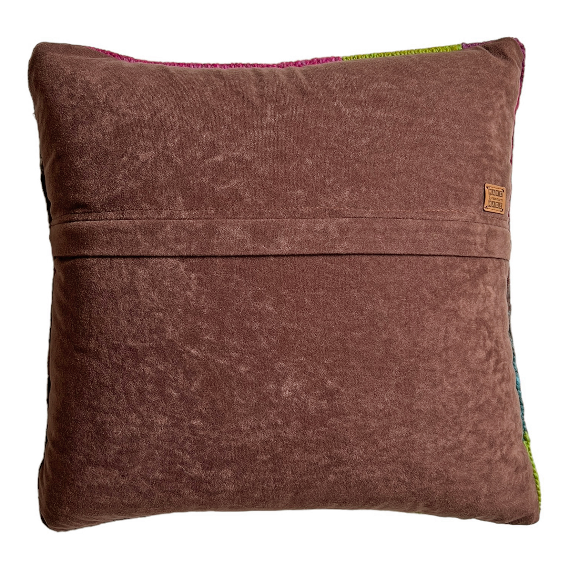 The back side of this pillow is a rich, chocolate-colored faux suede. A hidden zipper runs horizontally through the middle of the pillow and includes a leather Make & Made Fiber Crafts label.