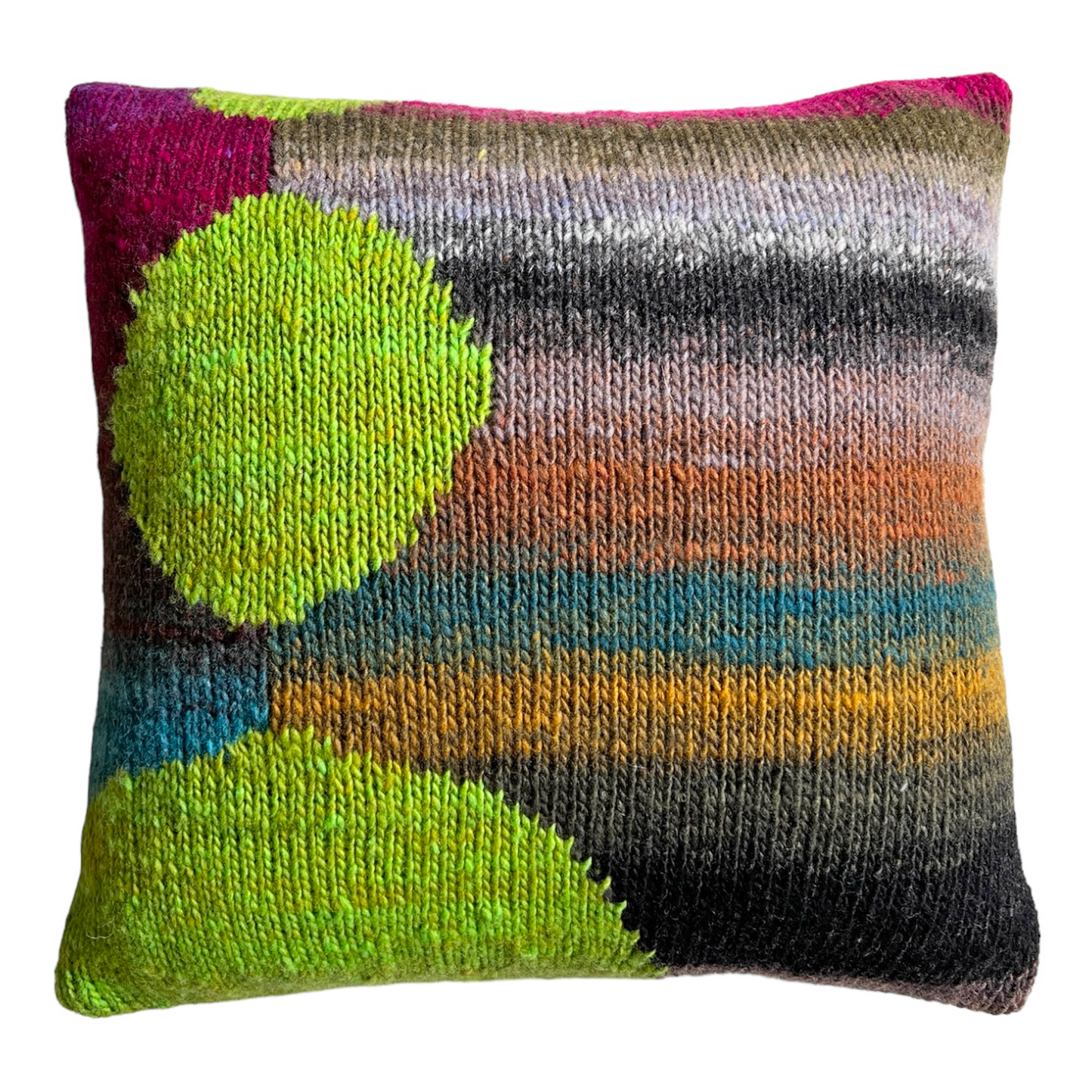 The hand-knit side of this pillow features a self-striping background in rich earthy tones including charcoal, gold, rust, gray, turquoise, and a hint of magenta. Three unequal spheres in bright lime are stacked vertically along the left side.
