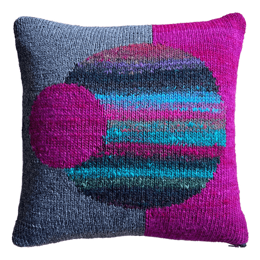 This decorative throw pillow featuring bold geometric spheres is hand-knit with 100% wool in shades of magenta, gray, turquoise, and black.