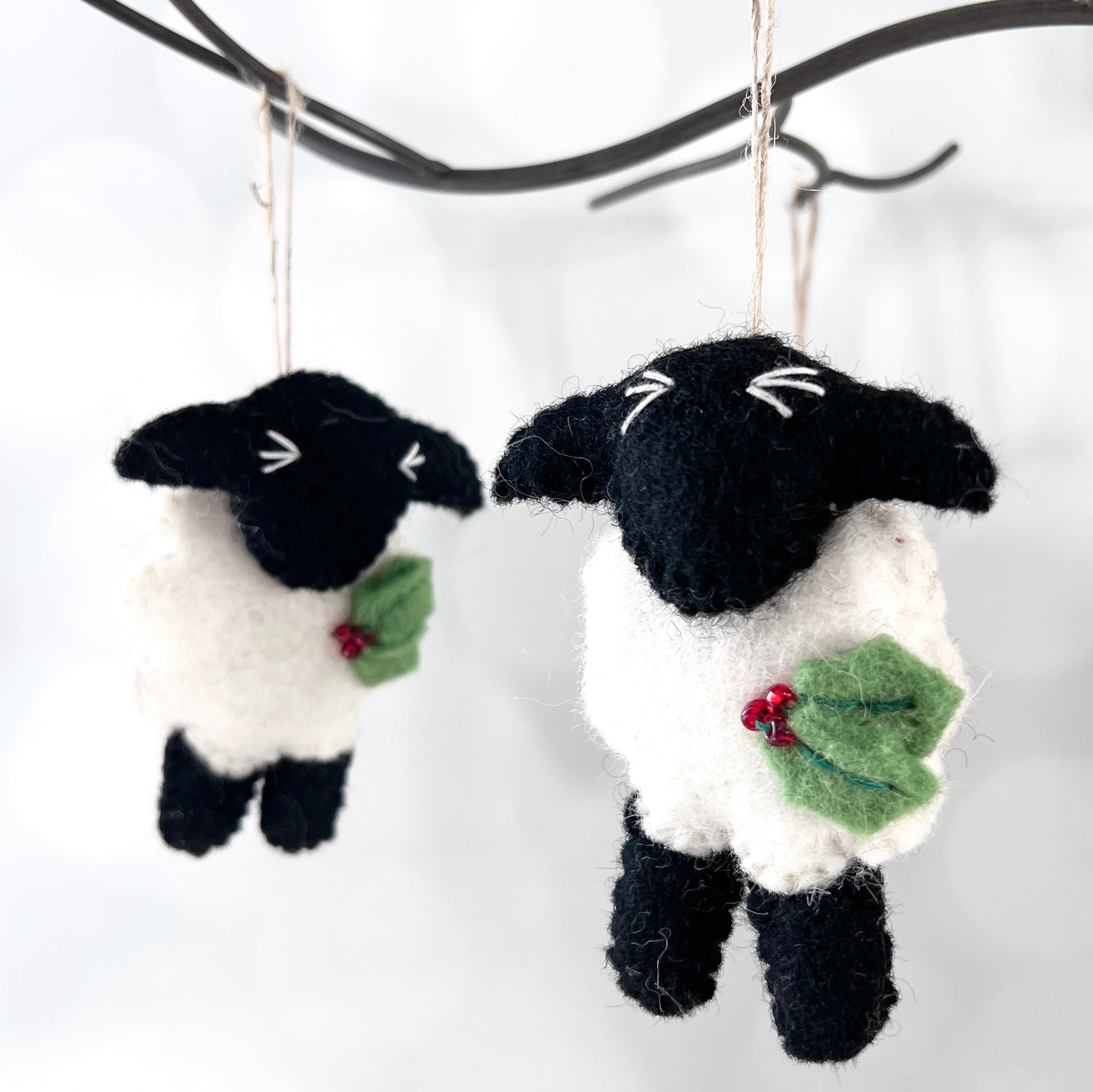 These adorable black and white felted sheep are adorned with a sprig of green felt holly with red glass bead berries.