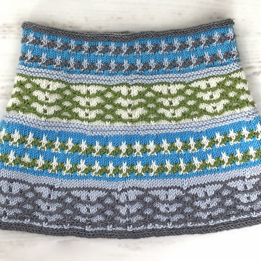 This cowl features bands of intricate colorwork in various combinations of turquoise, gray, sage green, and ivory. 