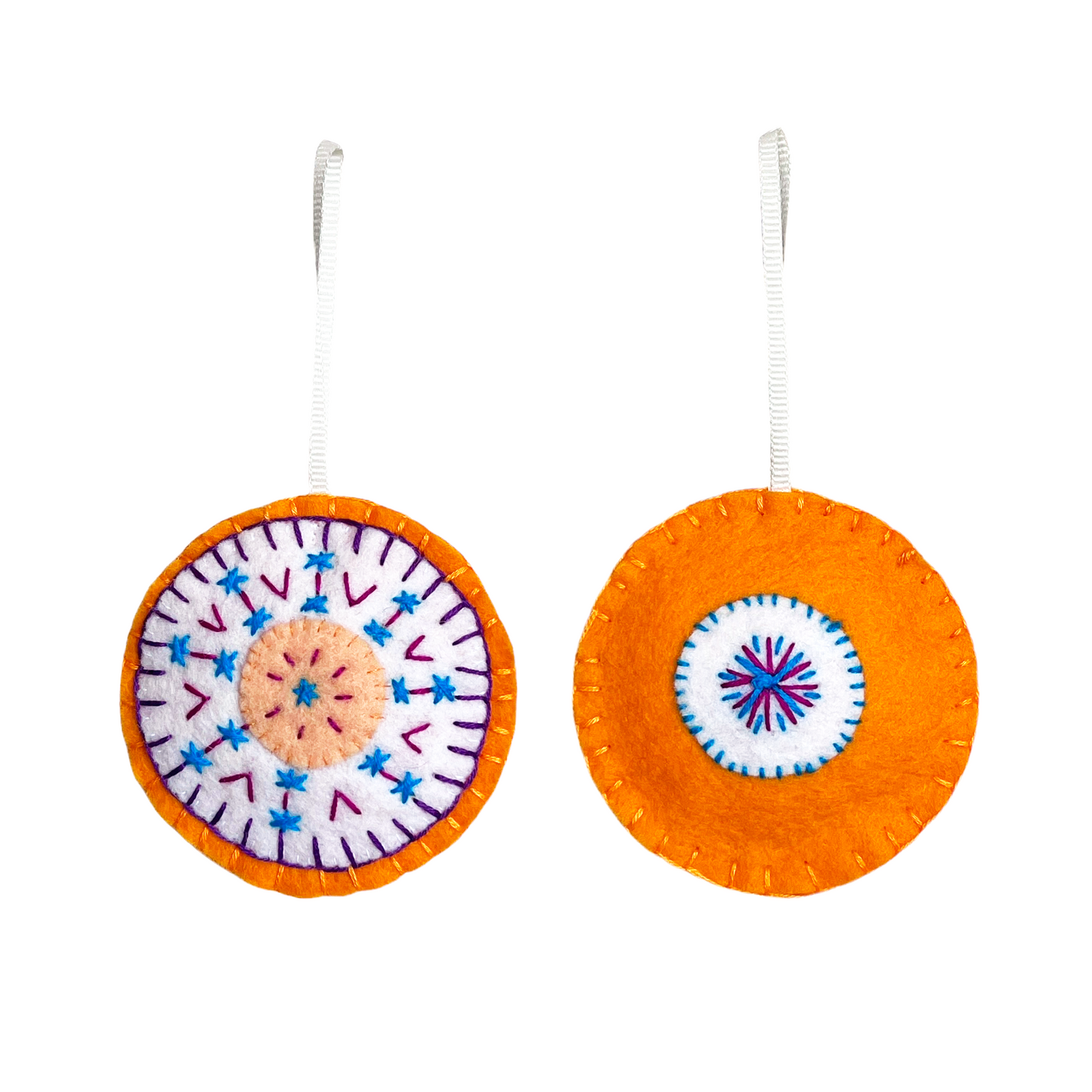This Mini Mandala ornament features concentric circles of peach, white, and orange felt with a matching orange felt back. Both sides are embroidered using purple, magentaq, and turquoise threads in a symmetrical, mandala-inspired design.