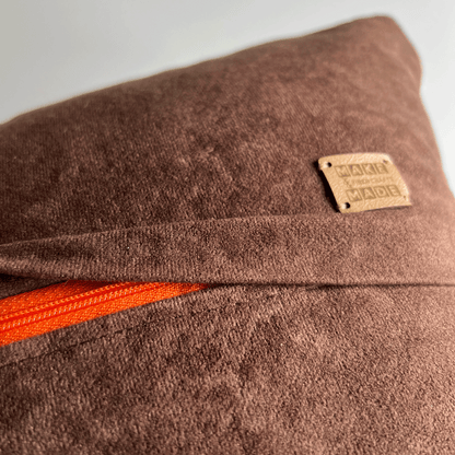 A bright orange zipper hides beneath a 1 inch flap, rendering this hand-sewn pillow cover easy to remove for spot cleaning.