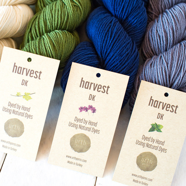 Multiple skeins of Urth's Harvest DK Yarn (dyed by hand using natural dyes) on a table in various colors